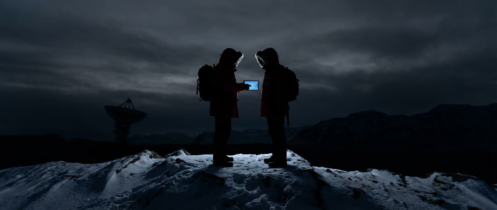 Two researchers consulting a tablet at a remote field station